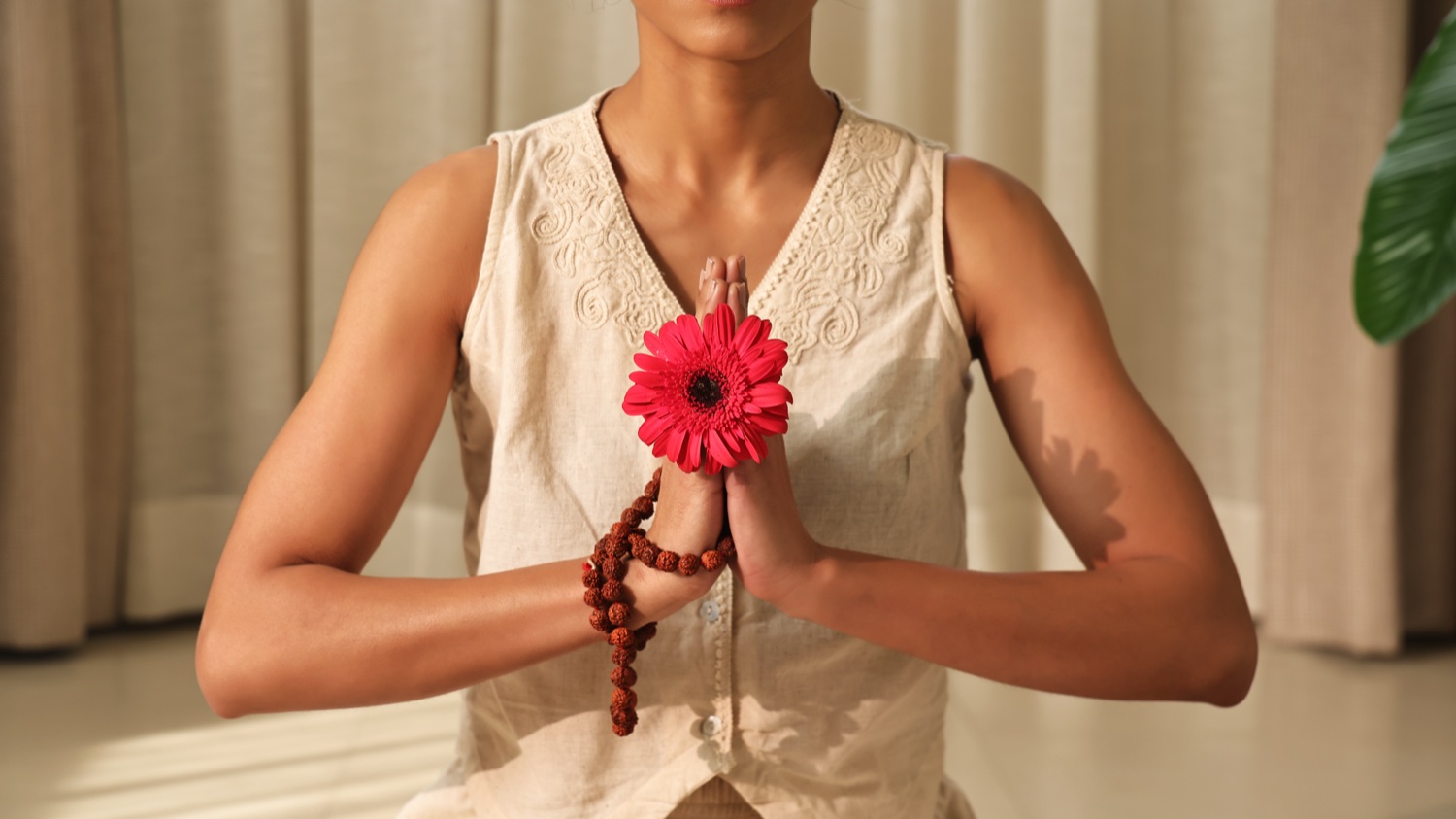 Donna con un fiore in un gesto Namaskar per Art of Vedas